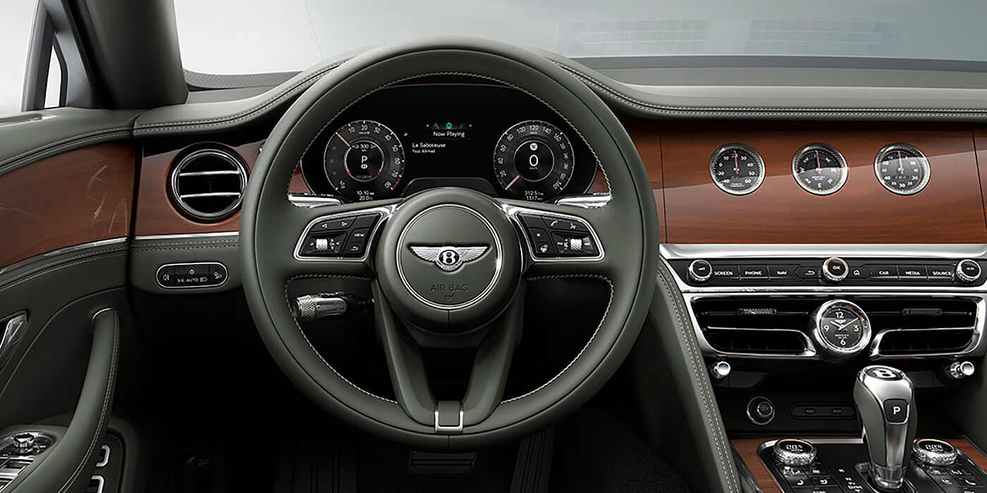 Bentley Abu Dhabi New Bentley Flying Spur sedan front cabin in Cumbrian Green hide and Crown Cut walnut veneer showing steering wheel and Rotating Display with three clocks on face