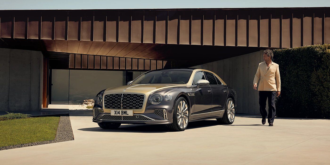 Bentley Abu Dhabi Bentley New Flying Spur Mulliner V8 hybrid sedan front three quarters in Rose Gold over Magnetic paint, parked near modern home