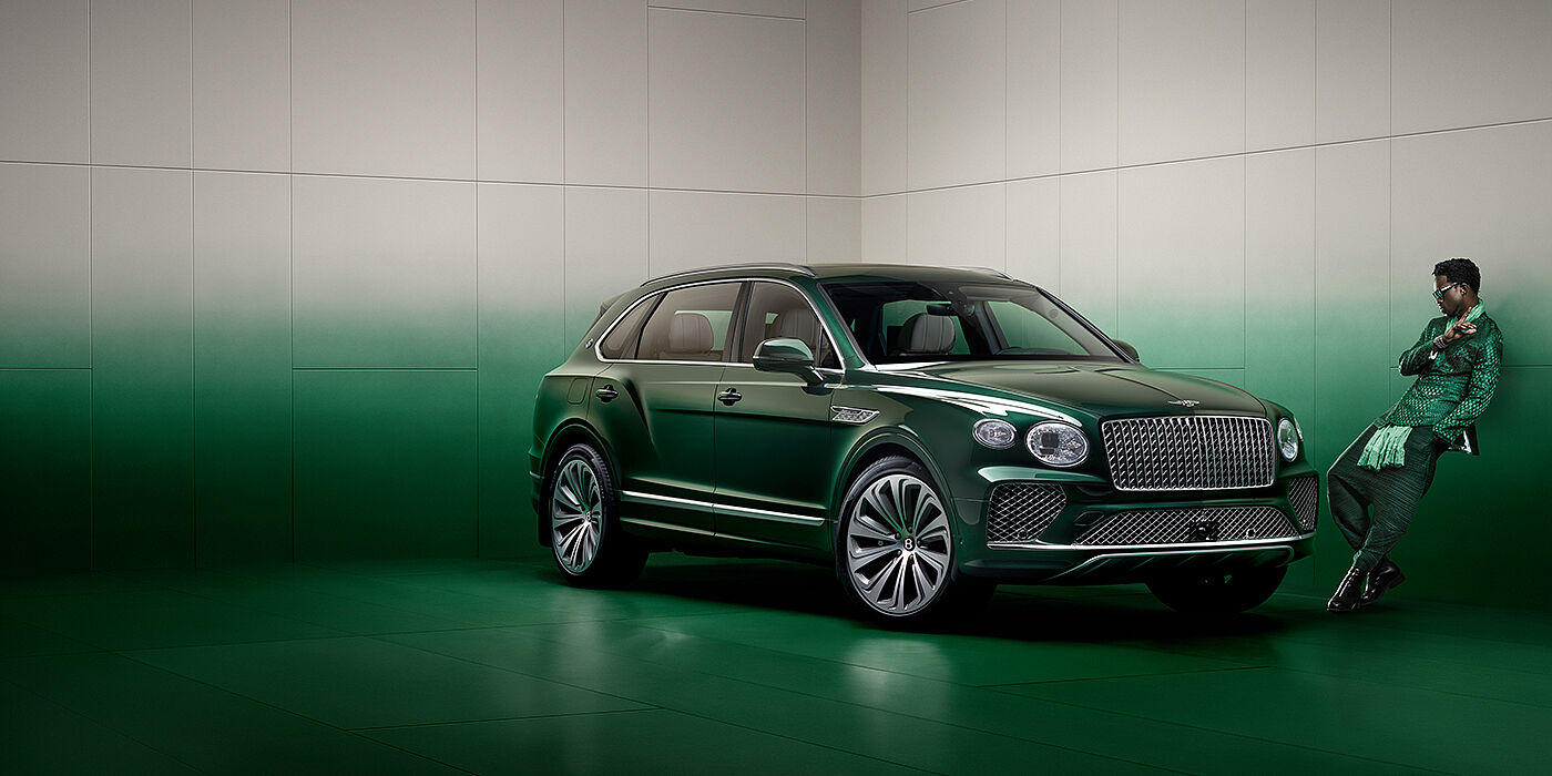 Bentley Abu Dhabi Wisdom K leans against wall next to Bentley Bentayga Extended Wheelbase Atelier Edition SUV in Light Emerald green paint