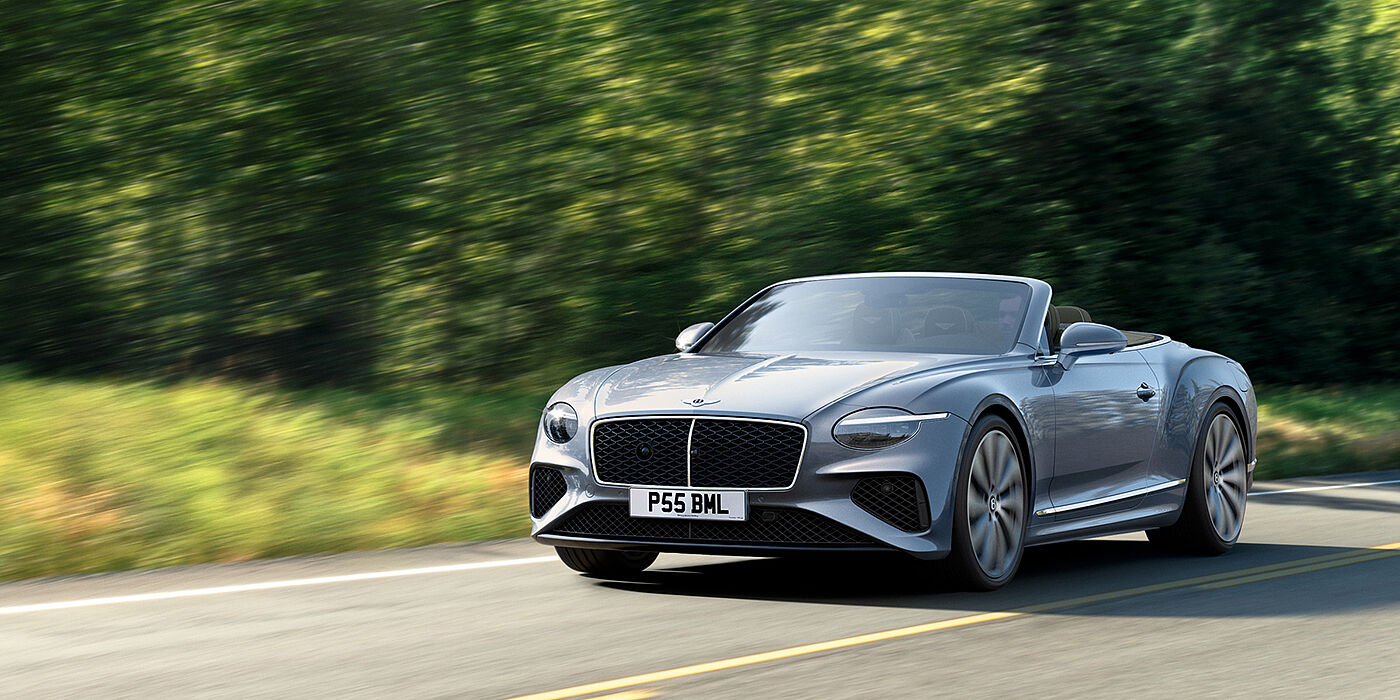 Bentley Abu Dhabi New Bentley Continental GTC convertible front view in Silverlake paint with 22 inch ten spoke wheels, driving dynamically on a country road